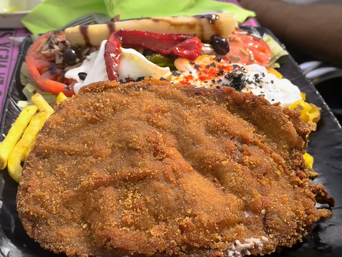 Cachopo de ternera empanado con ensalada, pimientos y huevo