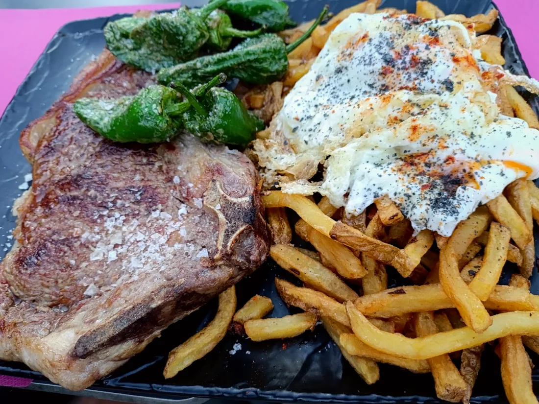Chuletón a la brasa con patatas, pimientos del padrón y huevo